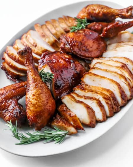 sliced chicken on a serving platter with rosemary sprigs