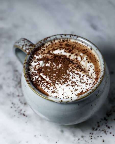 Hot chocolate in a mug with whipped cream and dust of cocoa powder on top