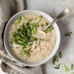 bowl of congee or rice porridge, garnished with scallions and cilantro