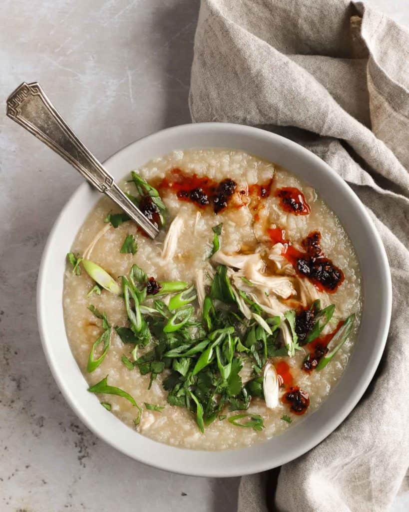 bowl of congee or rice porridge, garnished with scallions and cilantro