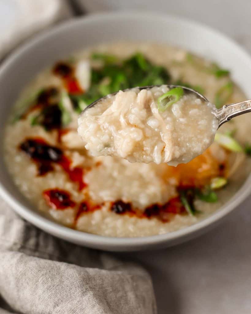bowl of congee or rice porridge, garnished with scallions and cilantro